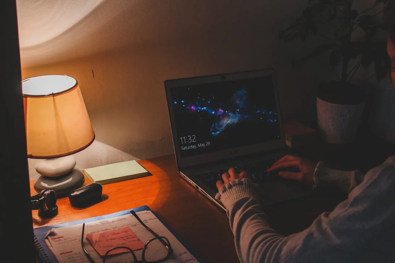 Mit KI Geld verdienen bedeutet echte Arbeit: Person sitzt abends konzentriert am Laptop